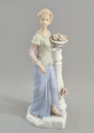 Antigo bibelot em porcelena, no estilo Laddró, representando dama com flores. Sem marca. Discreto fio de cabelo na base. Med.