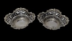 Duas pequenas cestas em metal espessurado a prata, com corpo vazado em delicado trabalho rendilhado, bordas recortadas e ornamentação em motivos florais estilizados, com elegante acabamento vazado em toda a estrutura. Medidas: 13,7 x 4 cm (cada).