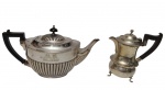 Dois bules em metal espessurado a prata, ambos com alças em madeira escuro. Um apresenta corpo bojudo com caneluras em relevo e tampa ornamentada; o outro possui corpo torneado, base elevada sobre pés e tampa articulada. Medidas: 28 x 13 x 15 cm / 15 x 15 x 8 cm.