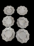 Seis salvas produzidas em metal espessurado a prata, com bordas recortadas e vazadas em decoração arabesca, apresentando gravações florais no espelho central. Diâmetro: 17,5 cm cada.