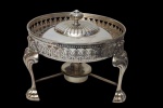Antigo réchaud circular, produzido em metal espessurado a prata, com tampa removível, estrutura vazada em galeria decorativa e pés estilizados. Acompanha queimador. Medidas: 17 x 24 cm.