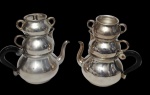 Lote contendo 2 conjuntos para chá da marca Wolff, produzidos em metal espessurado a prata, cada conjunto composto por bule, leiteira e açucareiro. Um dos açucareiros está sem tampa. Altura dos bules: 17 cm.