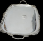 Grande e imponente bandeja de serviço, produzida em metal espessurado a prata, bordas recortadas e alças laterais ornamentadas em relevo. Medidas: 76 x 46 cm. Marcada ao fundo.