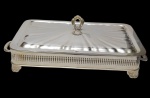 Porta pirex produzido em metal espessurado a prata, laterais vazadas, pegas laterais e tampa com pega cinzelada.Medindo: 37 x 23,5 x 15 cm.