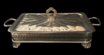 Porta pirex produzido em metal espessurado a prata, laterais vazadas, pegas laterais e tampa com pega cinzelada. Medindo: 40 x 21 x 13 cm.