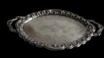 Grande imponente bandeja produzida em metal espessurada a prata, bordas e alças laterais com decoração em relevo e parte central ricamente cinzelada. Medindo: 57 x 32 x 3 cm.