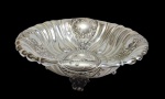 Fruteira/ centro de mesa em metal em metal espessurado a prata no formato oval, bordas onduladas, pés e parte  central ricamente cinzelados. Medindo: 36 x 26 x 7,5 cm.