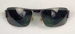 POLO RALPH LAUREN. Óculos de sol com armação em metal cromado e hastes largas em acetato preto. Lentes fumê em formato retangular. Apresenta logotipo do cavaleiro da marca aplicado nas hastes. Acompanha estojo original da marca.