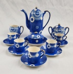 Conjunto de café em faiança japonesa azul com desenhos circulares brancos, composto de: bule, leiteira, açucareiro, manteigueira e 5 xícaras com pires (uma xícara com craquelê). Total: 9 peças. Medindo: 10 x 12 cm, 18 x 17 xm e 14 x 13 cm.