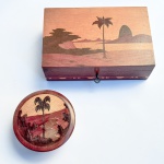 Duas caixas de coleção em madeira com marqueterie com representação iconográfica do Rio de Janeiro. Possui chave. Med 22 x 14 x 7 cm e 12 cm de diâmetro. 