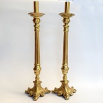 Par de castiçais em estilo neo clássico, confeccionado em bronze com base trípode decorada com folhas de acanto e volutas em relevo, fuste canelada. Med 49cm.
