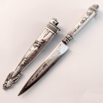 Faca gaúcha de coleção, cabo e bainha em metal banhado à prata ricamente cinzelado com cenas gaúchas em relevo e lâmina gravada com animais. Manufatura Corneta. Med 18cm. 