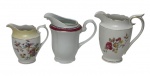Três leiteras em porcelana nacional, esmaltadas e policromada. Manufaturas ao verso. Medindo: 13,5 x 13,5 x 9 cm, 14 x 9 x 13 cm e 10,5 x 7,5 cm.