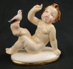 Estatueta em porcelana austríaca policromada, da marca GOLDSCHEINDER/VIENA, representando criança com pássaro pousado sobre pé. Decoração feito à  mão, medidas 10x10x45cm.