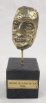 Escultura de bronze representando o rosto de Adolpho Block, criada pela artista plástica RUTH KAC. Possui base em mármore negro e a inscrição Prêmio Adolpho Block 2008, medidas 23cm.