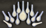 China. Quatorze colheres  em porcelana chinesa, com decoração em policromia azul sobre fundo branco, apresentando motivo central de dragão e borda ornamentada com frisos geométricos em estilo oriental. Padrão Grão de Arroz. Medindo: 10 cm à 23 cm.