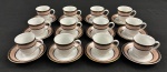 Schmidt. Doze xícaras para café em porcelana nacional padrão Gold, esmaltada na cor branca, com composição geométrica delicada em tons suaves. Borda ornamentada por uma faixa em rosa-claro com desenho em losangos entrelaçados, formando uma trama contínua e sutil. Essa faixa é emoldurada por frisos em marrom escuro, enriquecidos com pequenos detalhes dourados e filetes pontilhados. Manufatura no verso.