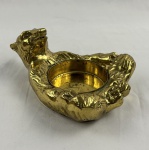 Urso em bronze, em modelagem estilizada formando cinzeiro, com o animal reclinado e cavidade circular central para apoio. Medindo 10 x 22 x 16 cm.
