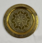 Prato decorativo em metal dourado, com decoração gravada em estilo arabesco e composição geométrica central em estrela de inspiração mourisca, cercada por frisos ornamentais em toda a borda. Medindo 25 cm de diâmetro.