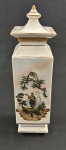Pote em porcelana com tampa, de formato retangular alongado, com decoração em estilo oriental/pastoral policromada, representando cenas figurativas em ambas as faces, enriquecidas por delicados filetes dourados nas bordas e na tampa. Corpo com linhas geométricas elegantes, encimado por tampa com pega em formato piramidal. Apresenta bicado na tampa. Medindo 32 x 8,5 x 8,5 cm.