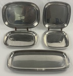 Conjunto de baixelas Meridional, Aço Inox 18/10 (5 Peças). 01 travessa grande: 53 cm x 22 cm, 01 travessa média: 40 cm x 28 cm, 01 travessa pequena: 34 cm x 24,5 cm, 01 travessa quadrada/funda: 26 cm x 26 cm, 01 travessa quadrada/rasa: 24 cm x 24 cm.