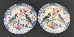 Par de placas decorativas de parede produzidas em metal, com decoração policromada representando pássaros sobre galhos floridos, em composição de inspiração oriental, com predominância dos tons azul, branco e vermelho. Medindo: 20 cm.