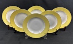 Mauá. Seis pratos fundos em porcelana esmaltada com borda amarela sobre fundo banco. Filetes em ouro. Manufatura no verso. Medindo: 3,5 x 23 cm.