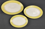 Mauá. Três travessas a em porcelana esmaltada com borda amarela sobre fundo banco. Filetes em ouro. Manufatura no verso. Medindo: 28 x 18 cm à 34 x 24 cm.