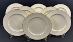 RC Bone China by Noritake, Japan. Oito pratos rasos em porcelana esmaltada, em tom marfim, com bordas decoradas em relevo com arabescos e delicado friso em ouro na borda, com acabamento refinado e decoração em baixo-relevo. Medidas; 27 cm.
