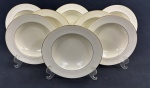 RC Bone China by Noritake, Japan. Oito pratos fundos em porcelana esmaltada, em tom marfim, com bordas decoradas em relevo com arabescos e delicado friso em ouro na borda, com acabamento refinado e decoração em baixo-relevo. Medidas; 3,5 x 21 cm.