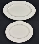 RC Bone China by Noritake, Japan. Duas travessas em porcelana esmaltada, em tom marfim, com bordas decoradas em relevo com arabescos e delicado friso em ouro na borda, com acabamento refinado e decoração em baixo-relevo. Medidas; 30 x 23 cm e 41 x 29 cm.