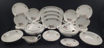 Real. Serviço de jantar em porcelana esmaltada, decorado com delicados motivos florais policromados sobre fundo branco e friso dourado nas bordas. Composto por 12 pratos rasos (25 cm), 12 pratos fundos (3 x 21,5 cm), 12 pratos de sobremesa (19 cm), 02 sopeiras com tampa (21 x 31 x 25 cm), 03 saladeiras (medindo de 6 x 22 cm a 6 x 26 cm), 05 travessas (medindo de 22 x 14 cm a 41 x 25 cm) e 01 molheira (10 x 21 x 11 cm). Manufatura no verso.
