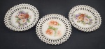 Três pratos decorativos esmaltado e policromado com motivos florais. Bordas fenestradas. Medindo: 15,5 cm.