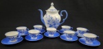 Schmidt. Conjunto para café em porcelana decorada em azul floral, composto por bule com tampa, altura 22 cm, 9 xícaras de café e 10 pires; contém xícaracbicada e desgaste nas pinturas.