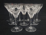 Nove (9) taças para vinho branco em cristal incolor, lapidado à mão com caneluras e coluna facetada, sendo 4 com bicados. Medida: 15 x 7,5 cm.