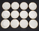 Hutschenreuther Hohenberg, Alemanha. Doze pratos para pão em porcelana alemã esmaltada na cor branca, borda com rendilhado em preto sobre fundo dourado. Manufatura ao verso. Medindo: 16 cm.  1 com fio de cabelo