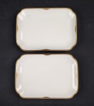 Hutschenreuther Hohenberg, Alemanha. Duas travessas em porcelana alemã esmaltada na cor branca, borda com rendilhado em preto sobre fundo dourado. Manufatura ao verso. Medindo:  18x25 cm.