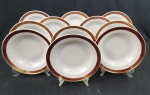 Onze pratos fundos em porcelana polonesa Karolina, na cor branca esmaltada, com abas em tom rubi decoradas por arabescos e folhagens em ouro, bordas filetadas. Medida; 3 x 24 cm. Apresenta marcas de desgaste na ornamentação em ouro.