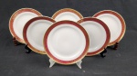 Seis pratos para sobremesa em porcelana polonesa Karolina, na cor branca esmaltada, com abas em tom rubi decoradas por arabescos e folhagens em ouro, bordas filetadas. Medida; 20 cm. Apresenta marcas de desgaste na ornamentação em ouro.
