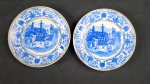 Dois pequenos pratos decorativos  em porcelana branca, decorada em azul, bordas com motivos florais e, ao centro, paisagem de casario, personagens e cavalos. Fios dourados nas bordas com algum desgaste. Diâmetro:.15 cm ap desgastes no dourado