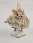 Escultura em porcelana esmaltada e policromada, representando dançarinas. Medindo: 16 x 14 x  8 cm. Avarias na saia.