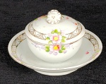 Manteigueira em porcelana branca japonesa, com decoração de flores, folhas e arabescos. Med.:9 x 15 cm.