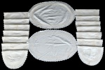 Connjunto em linho branco com bordado em ponto cheio.  A saber: A) Duas trilhas para mesa ovais (med.:  39 x 62 cm) e B) Quatorze jogos americanos ovais ( 32 x 45 cm). Atenção: Apresenta amarelado e pequenos furinhos, há registro nas fotos.