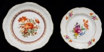 Dois pratos florais decorativos de porcelana com policromia e frisos dourados. Med. prato 1: 24cm de diâmetro; prato 2: 27cm de diâmetro.
