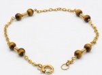 Pulseira de ouro 18k com contas esféricas de olho de tigre intercaladas.18 cm. Peso total bruto: 2.75g.
