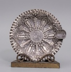 Cinzeiro em prata de lei ricamente cinzelado com relevos. Moeda central com efígie de D. Pedro II datada de 1889. Bordas onduladas e contrastes na lateral. Brasil, século XIX. Med.: 3 x 15 x 14cm. Peso: 146.3g