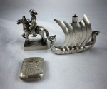 Três peças diversas em metal espessurado a prata, a saber: 1 cavaleiro da marca EBERLE, 1 caravela com marca na base e 1 fosforeira cinzelada com ramos de flores em relevo.
