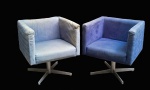 Par de poltronas com design contemporâneo no sentido quadrangular com mecanismos giratórios e pés cruzados em metal prateado. Estofamento no estado. Med.: 72 x 64 x 64cm.