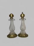 Par de bases de abajur com corpos bulbosos em vidro moldado e fosco, decorados por caneluras verticais e aplicações circulares em vidro incolor, assentados sobre bases metálicas relevadas, com montagens superiores igualmente ornamentadas. Produção provável da primeira metade do século XX. Encontram-se incompletas, sem cúpulas e instalação elétrica, apresentando oxidação, desgastes no metal, riscos e triscados aparentes. Medindo: