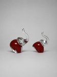 Par de esculturas decorativas em vidro maciço, trabalhado a quente, representando elefantes de trombas erguidas. Apresentam corpos em tonalidade vermelho-rubi, com cabeças, orelhas e trombas modeladas em vidro incolor, formando composição bicolor. Conjunto composto por duas peças de dimensões distintas. Sem assinatura, etiqueta ou marca de manufatura visível. Produção contemporânea, de origem não identificada. Bom estado geral. Medindo: